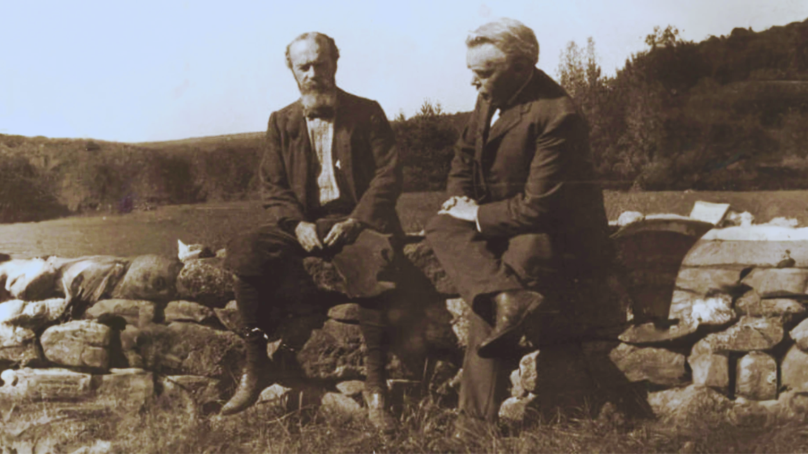 An image of the pragmatist philosopher William James sitting on a stone wall talking with the philosopher Josiah Royce.