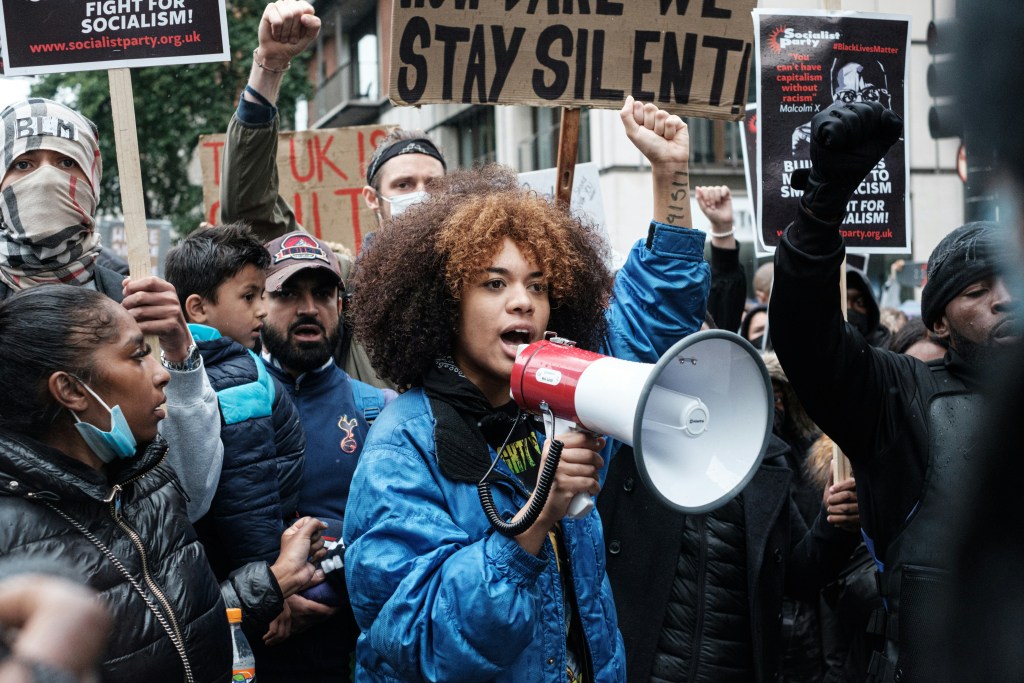 Activist holding up posters and one speaking into a bullhorn